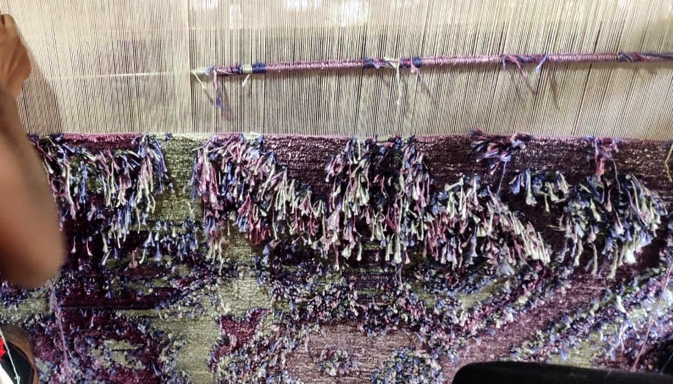 Bamboo silk being knotted onto the loom, the sheen catching light differently from wool