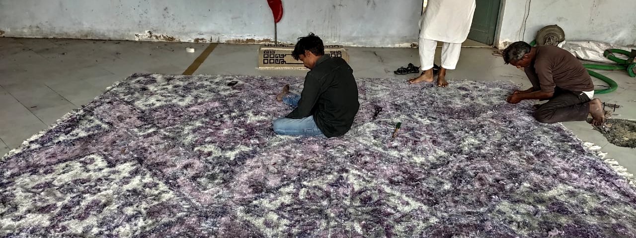 Artisans clipping the pile of the finished bamboo silk rug by hand