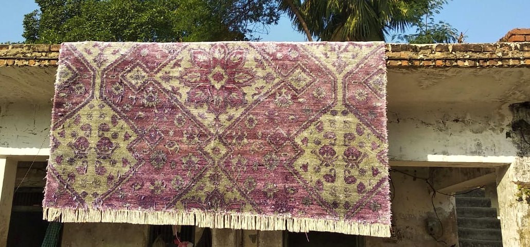 Stage 06 — a bamboo silk rug hung to sun-dry on a wall, an alternative to the ground frames