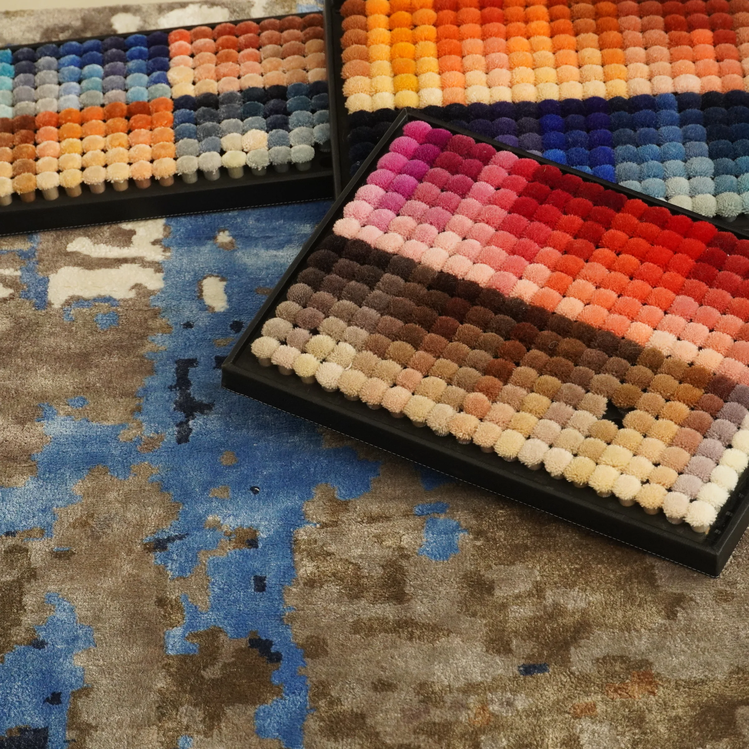 Multiple approved lab-dip swatches laid out on a bench beside a reference chart for cross-check