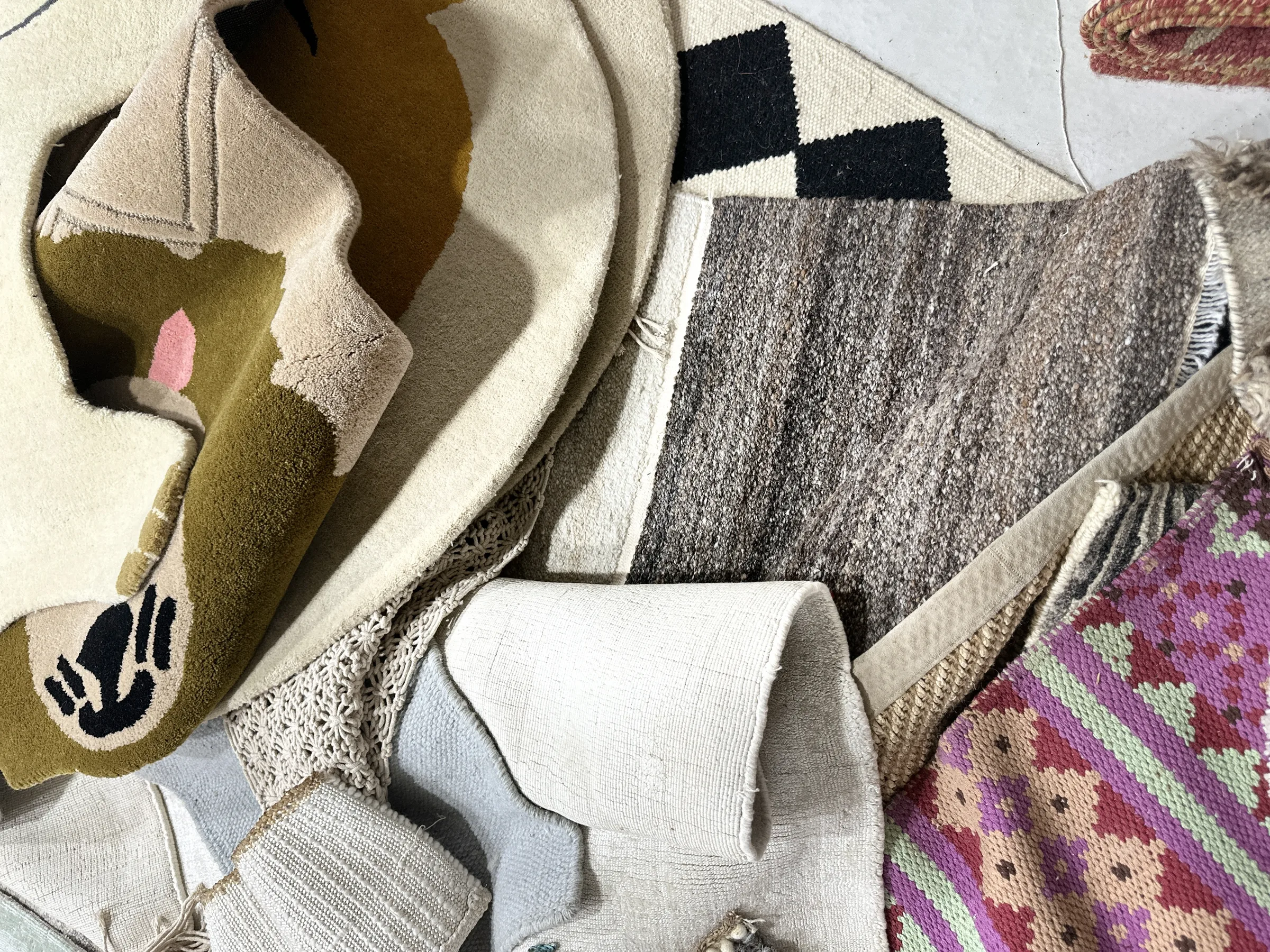 Second sample-library flatlay: mixed neutral weaves and pattern chips laid out on the sample table