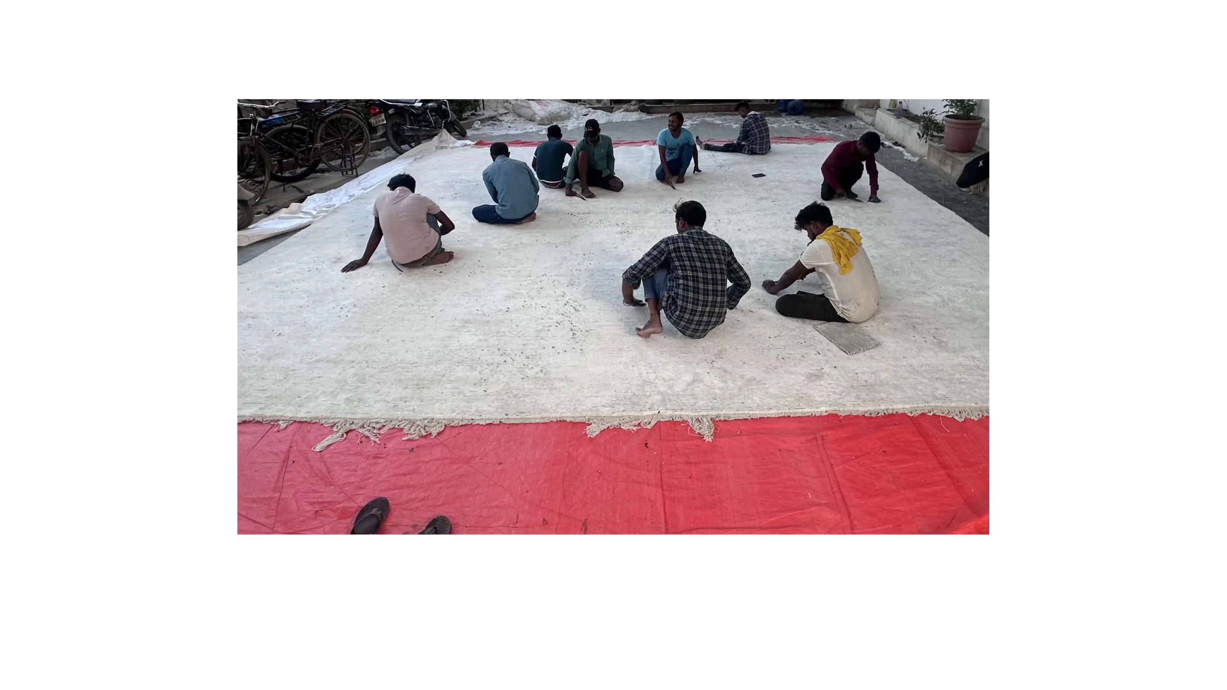 A wide view of finishers at work across the PiHue facility, several rugs in progress
