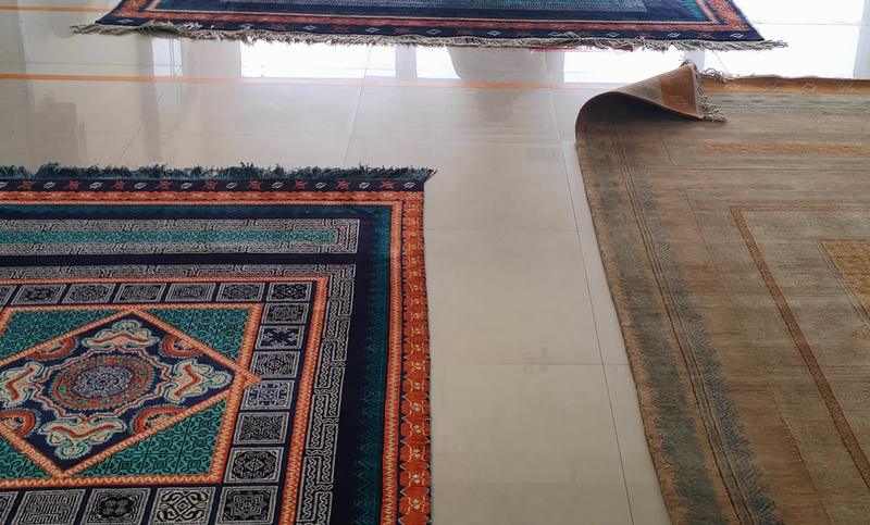 Hand-knotted rugs with medallion and border designs laid out flat for inspection