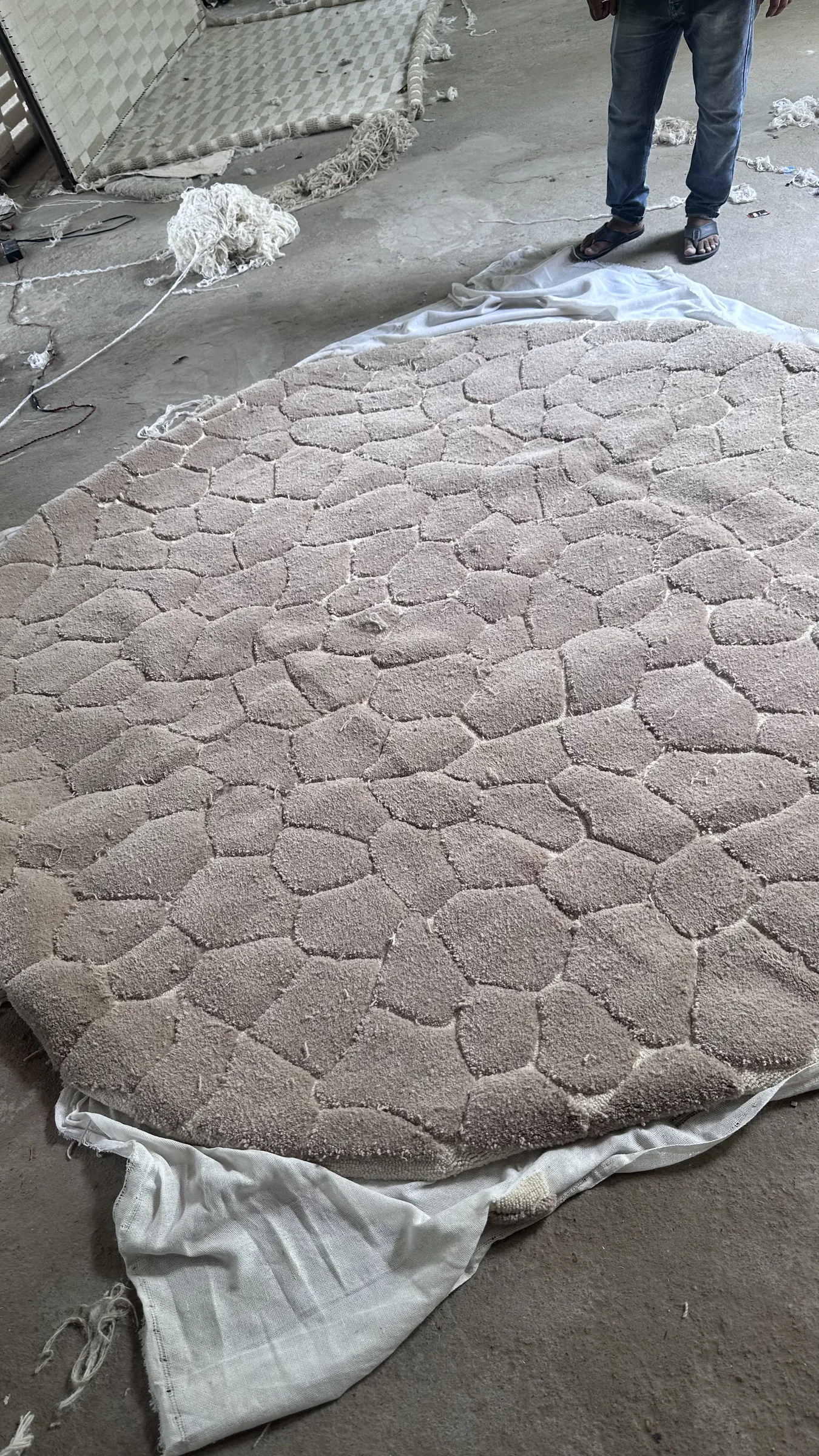 Close view of tufted pile emerging on the reverse of a stretched canvas as yarn is punched through