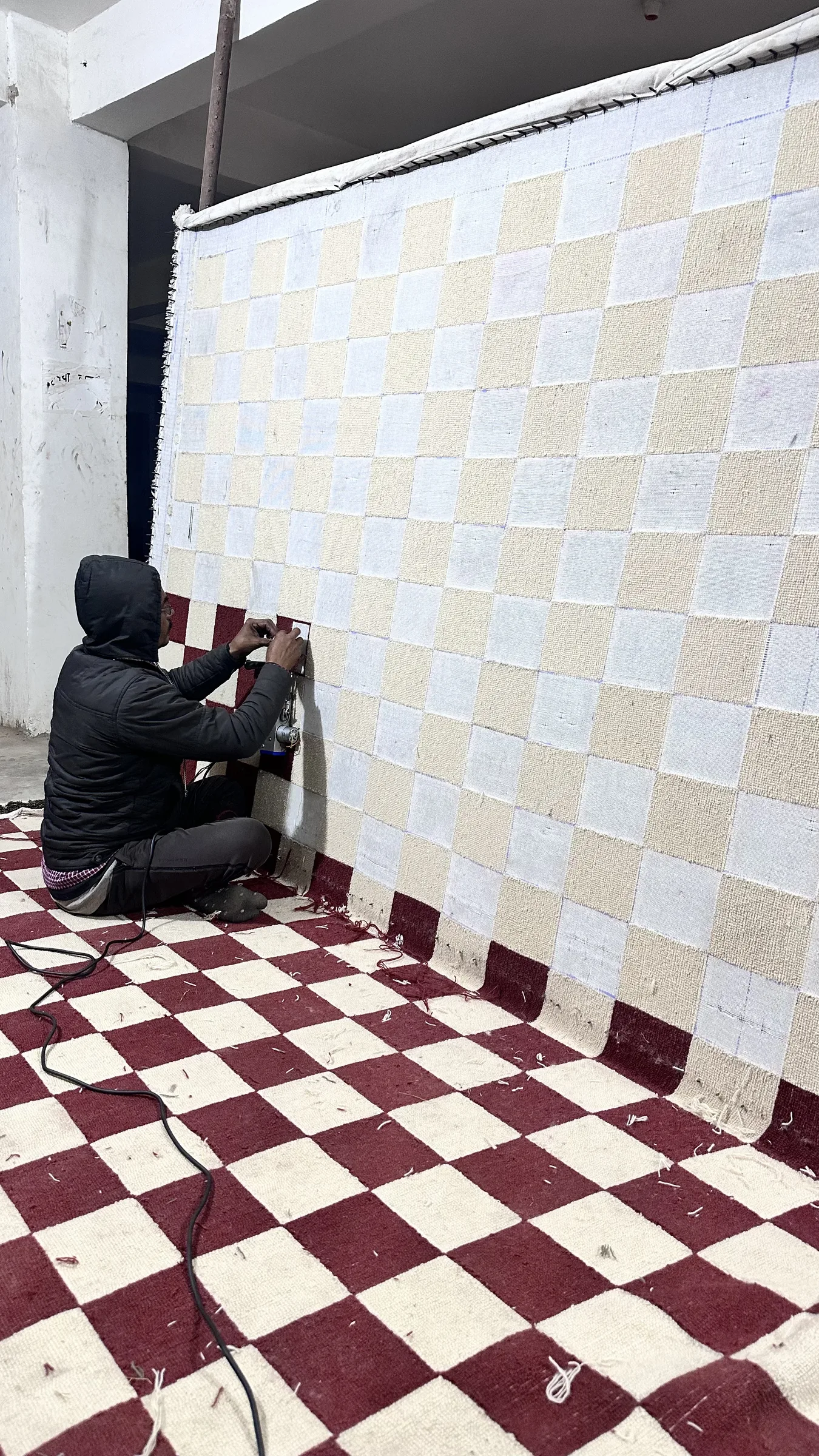 A finisher measuring the length of a finished tufted rug with a tape at the QC bench