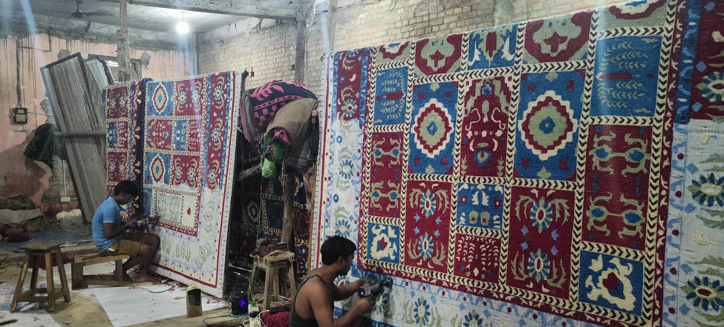 A tufter following a drawn design on stretched canvas, punching coloured yarn through row by row