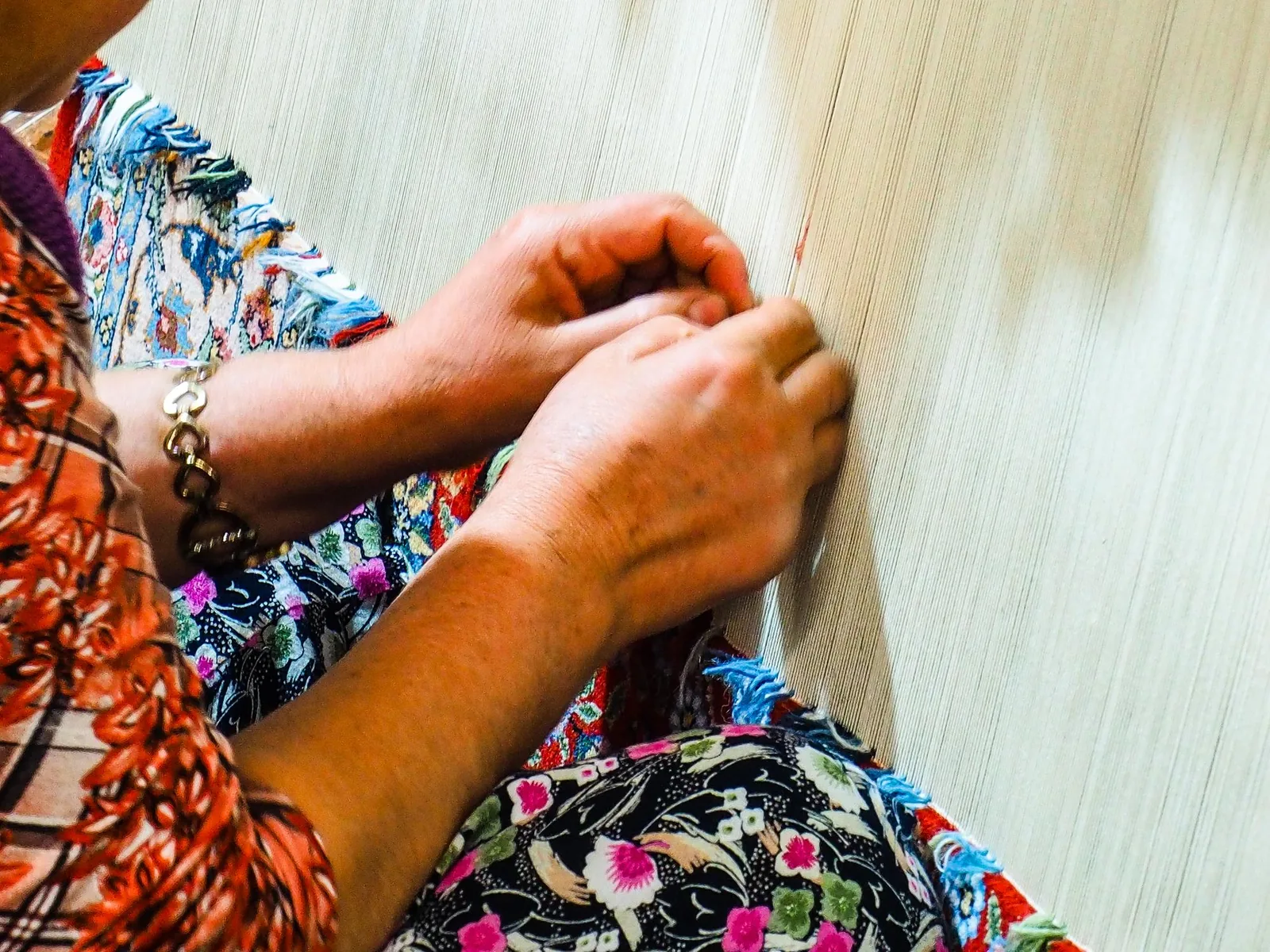 Hands tying knots on a rug in progress