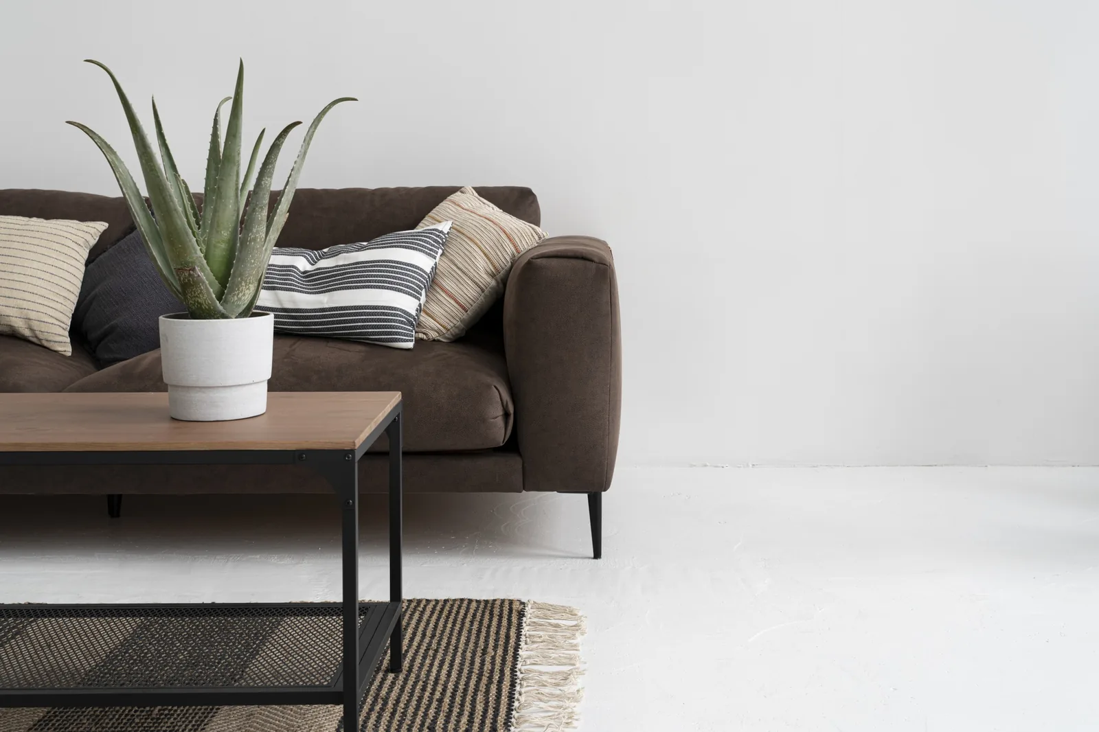 A jute rug on a white floor beneath a brown couch — natural fibre in a modern room