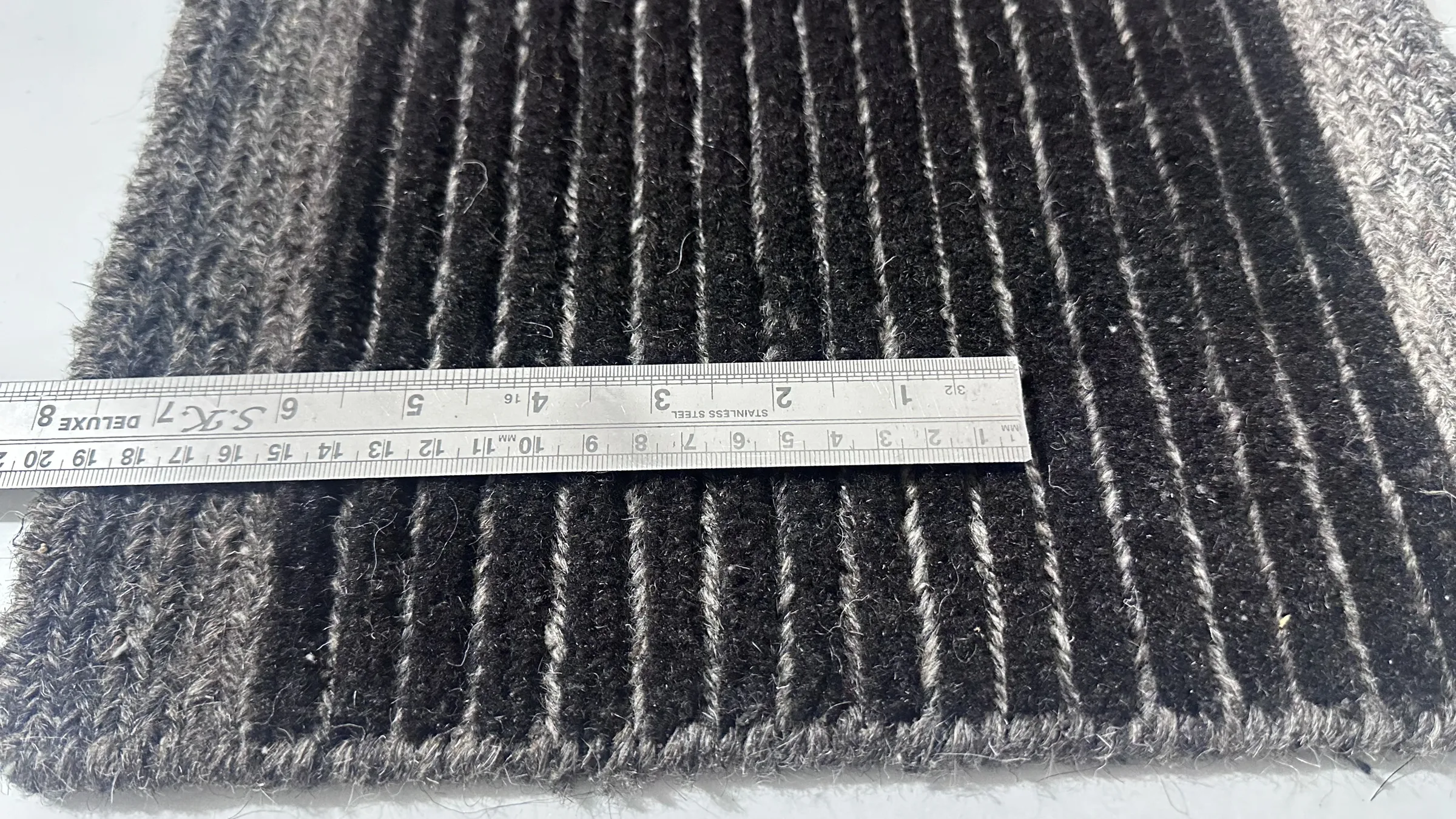 A supervisor inspecting the reverse of a hand-knotted rug for knot-density fidelity