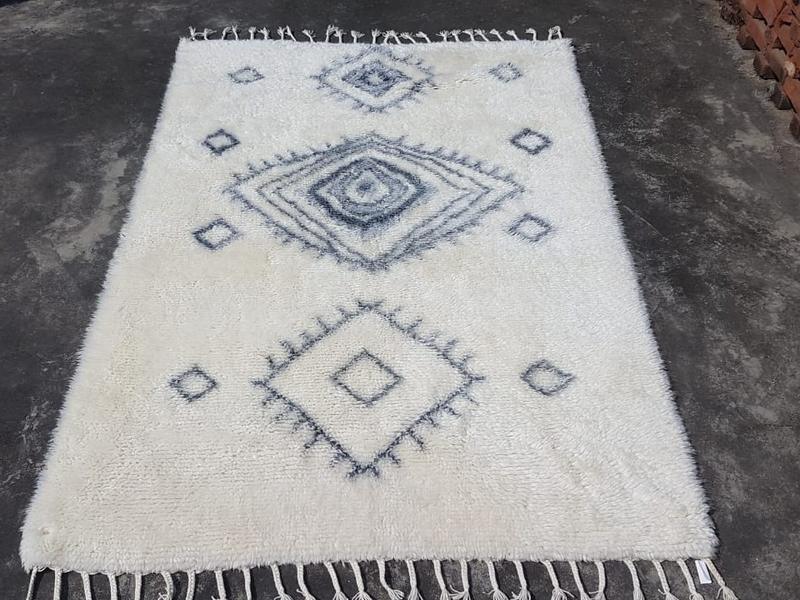 Ivory shag rug with concentric diamond motifs and hand-tied fringe, shown flat