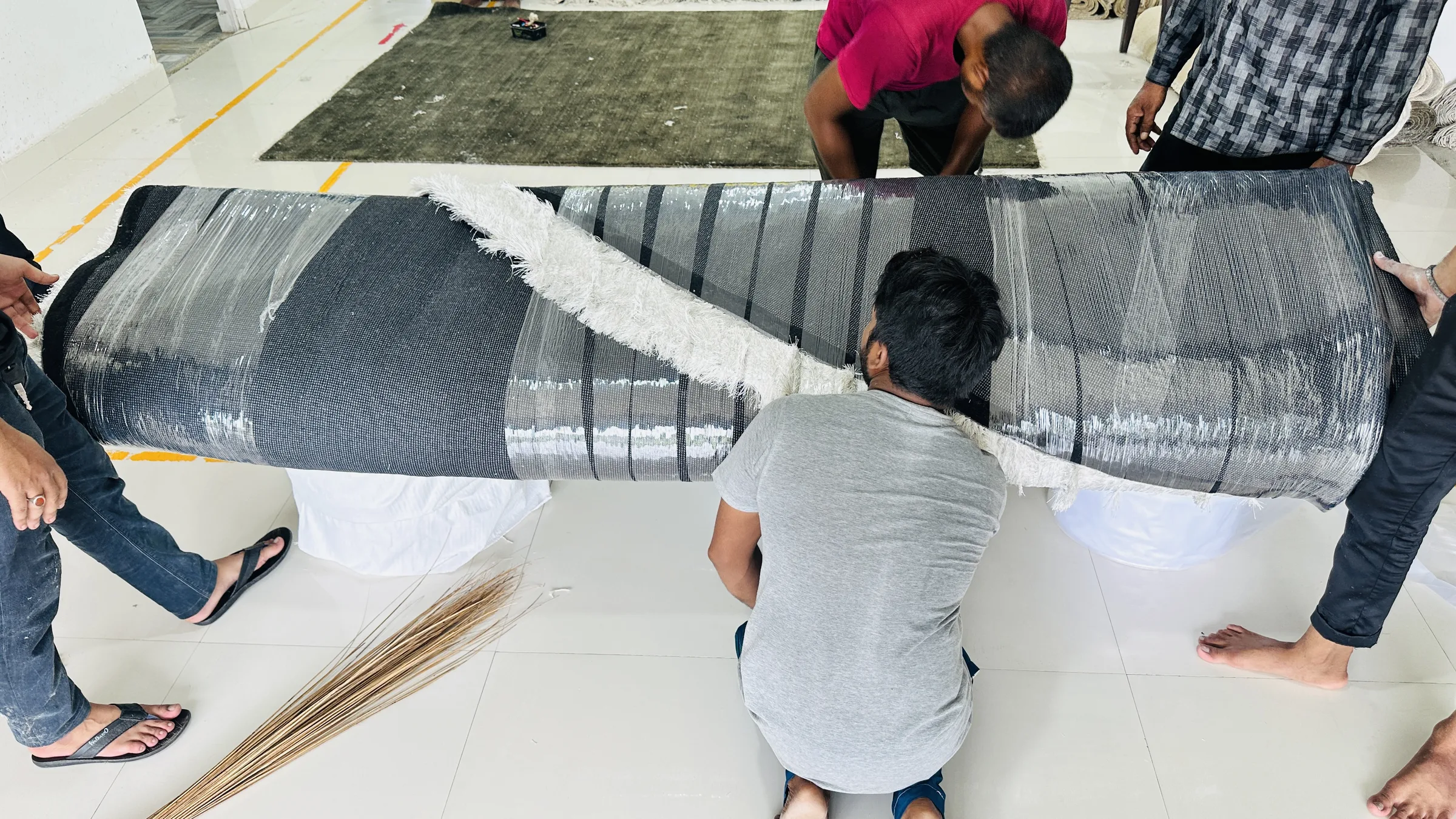 A finished rug being wrapped in white plastic sheet ahead of pallet-strapping