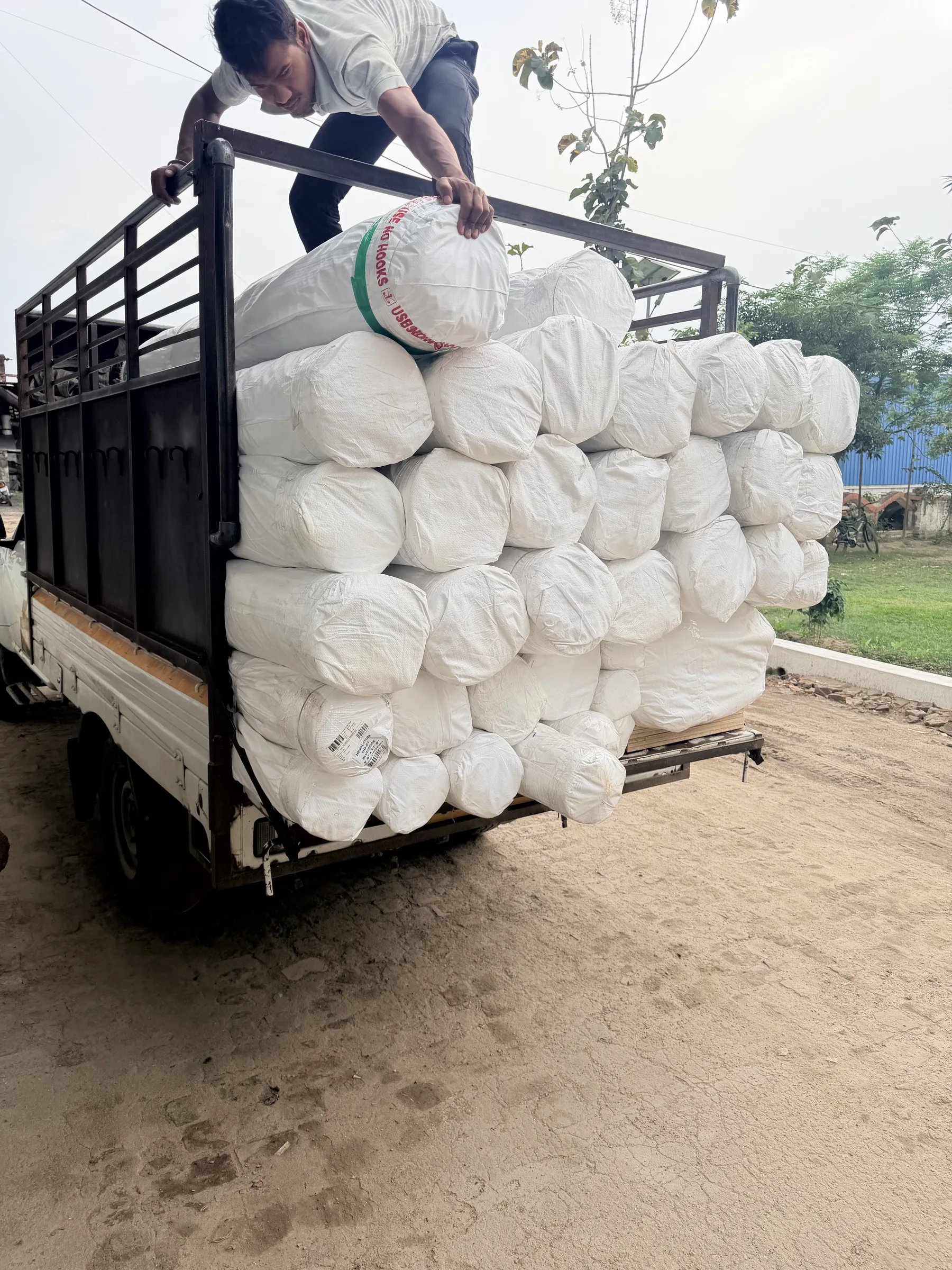 Rolled and wrapped rug bundles strapped for transit at the despatch bay