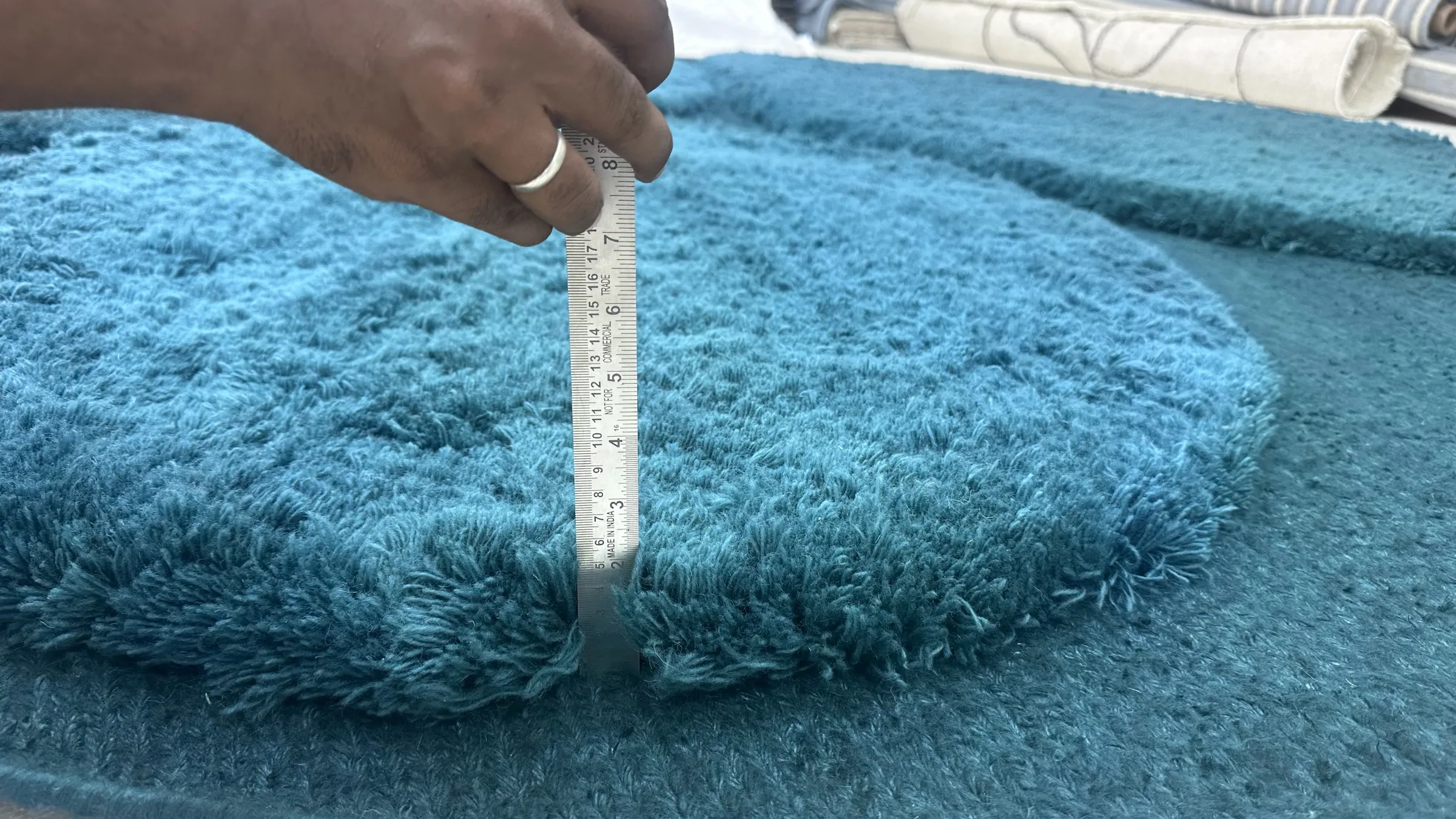 A pile-height gauge pressed against a finished hand-knotted pile to check specified depth