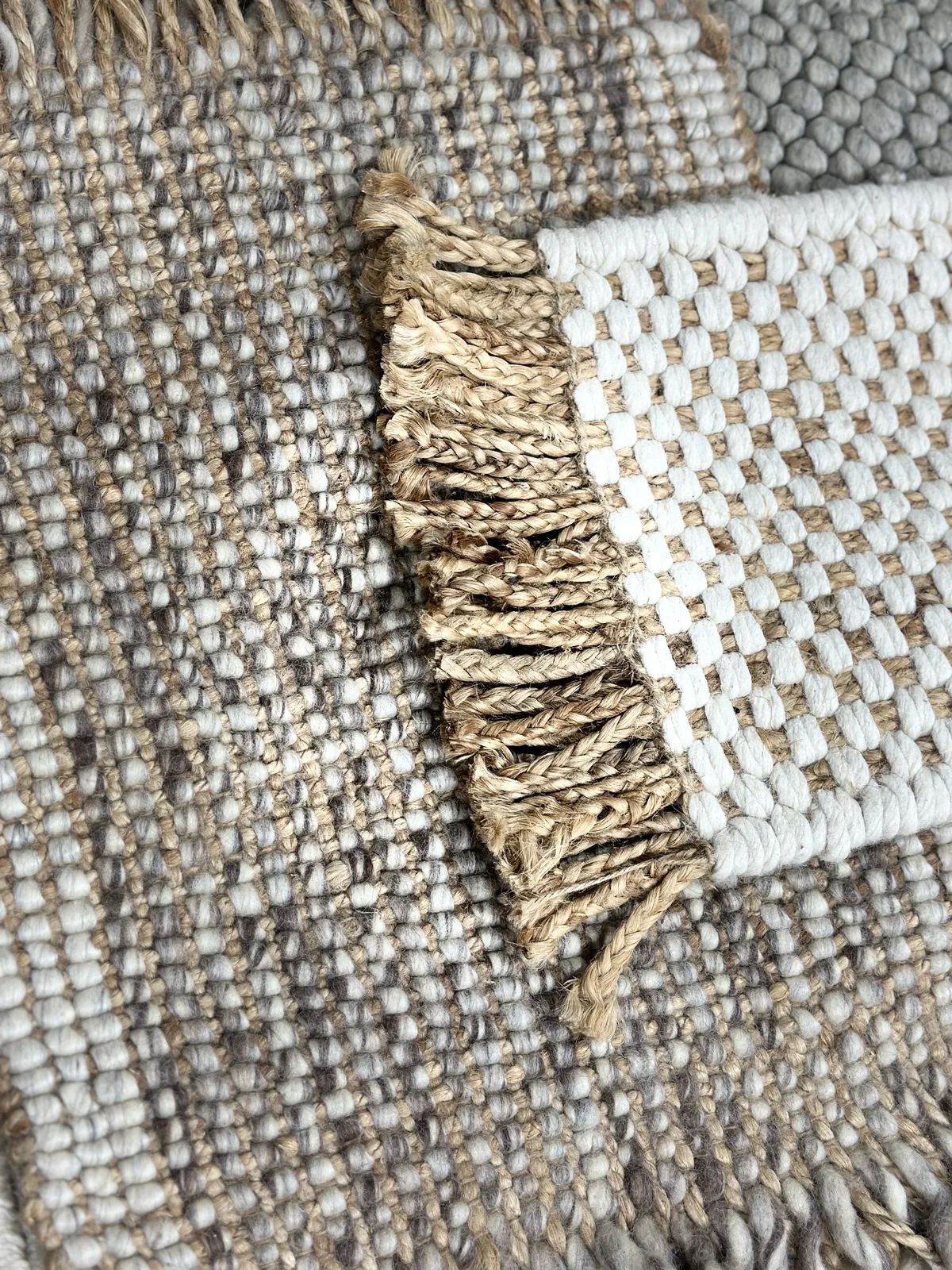 A close-up of natural-fibre rug edges with overlapping fringes &mdash; jute and wool textures