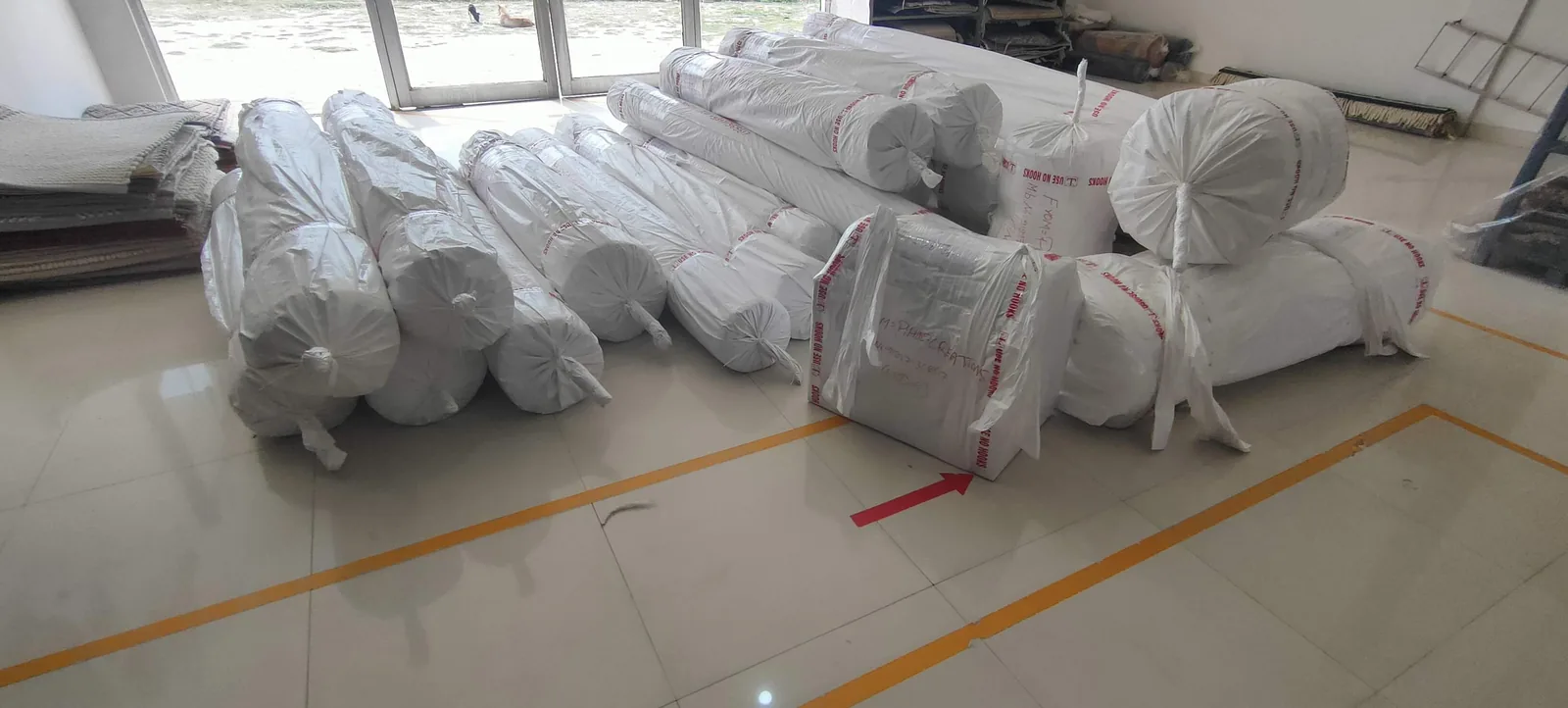 Wrapped rolled rugs lined up on the factory floor, ready for shipping