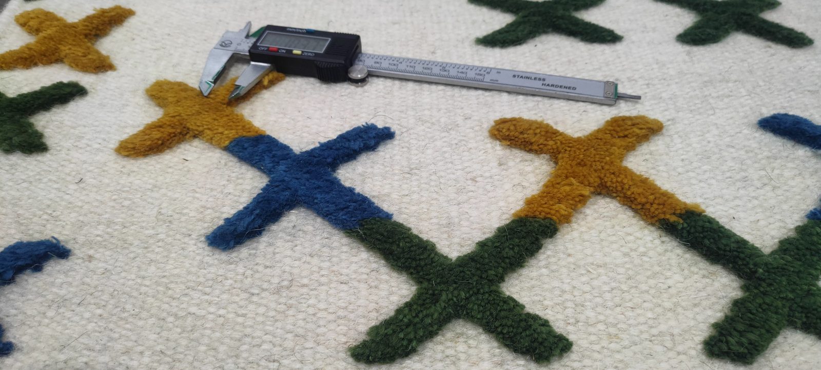 Stage 05 — measuring a rug against the specified size at receiving