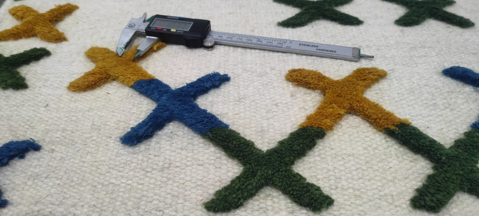 A rug on the QC bench being measured against specification with a digital caliper