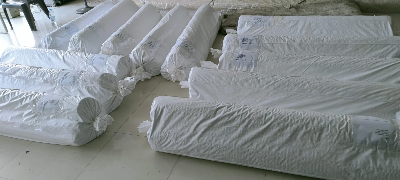 Wrapped rug bundles with SKU labels stacked on the packing bay floor