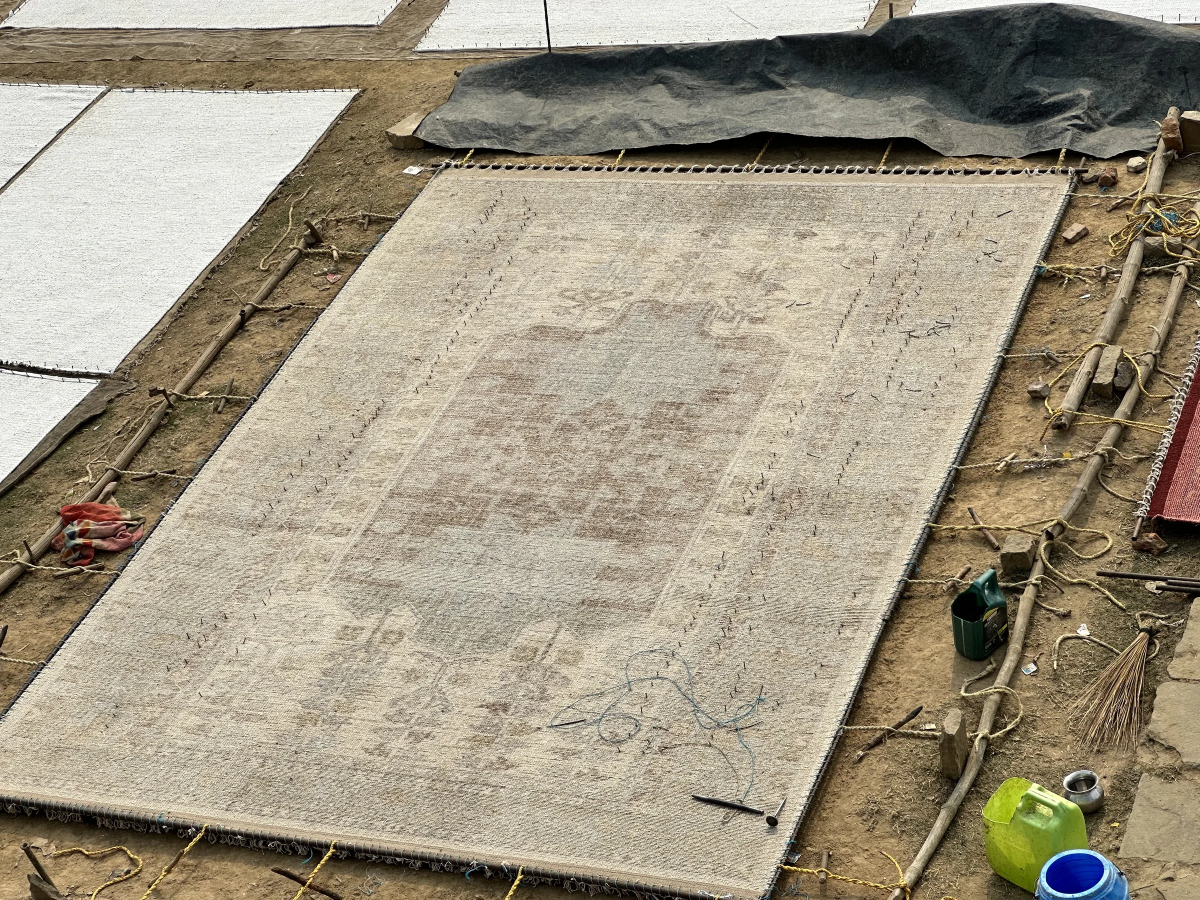 A rug stretched over a wooden frame in the finishing bay for truing