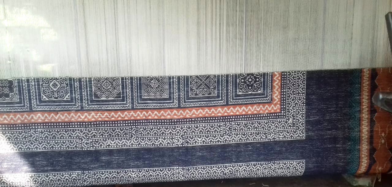 Stage 04 — a navy silk rug on the loom, border emerging row by row