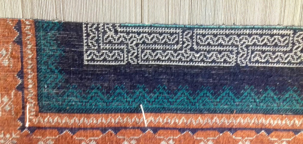Close-up of a hand-knotted silk rug, individual knots visible in the pile