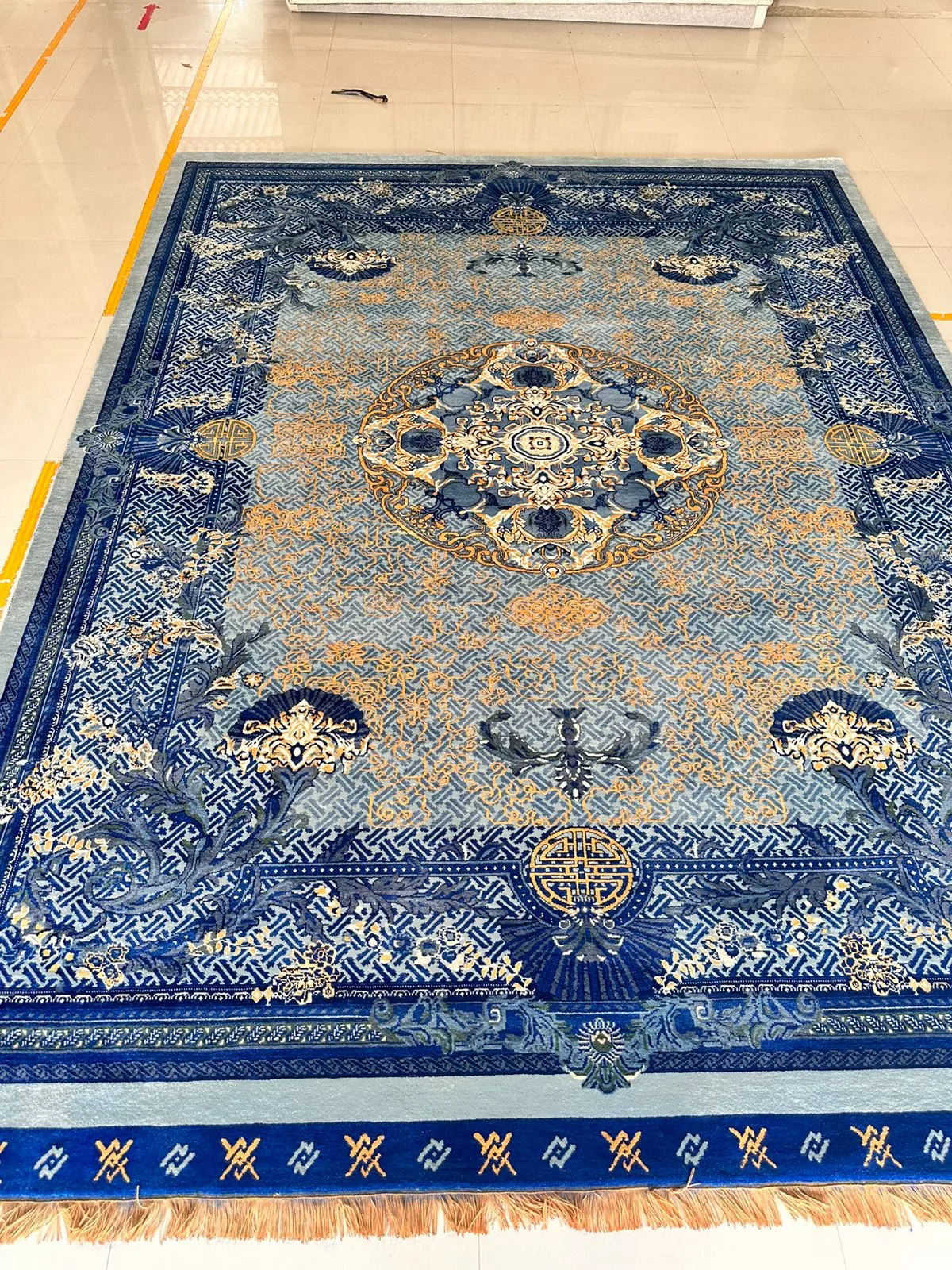 A finished hand-knotted rug in blue and gold with a traditional central medallion design