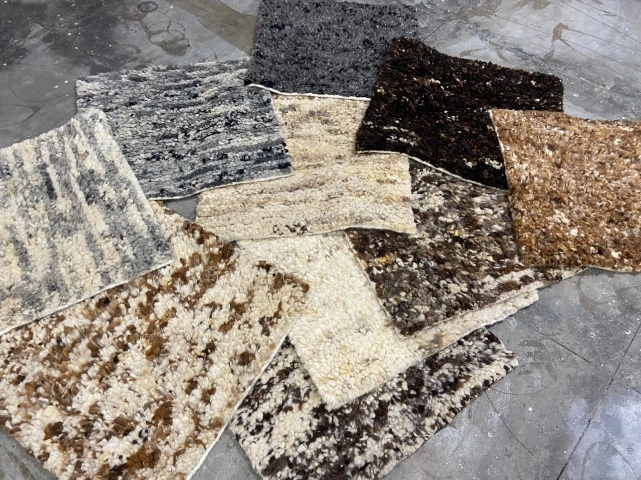 Stacked hand-carded natural wool samples in cream, brown and grey — the pre-dye colour range