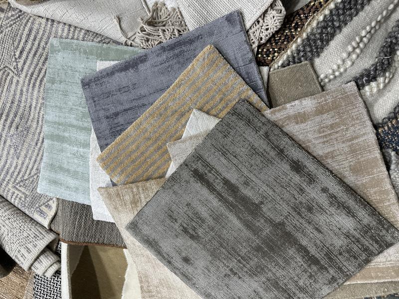 Fan of rug swatches in muted greys, greens and neutrals showing varied weave structures