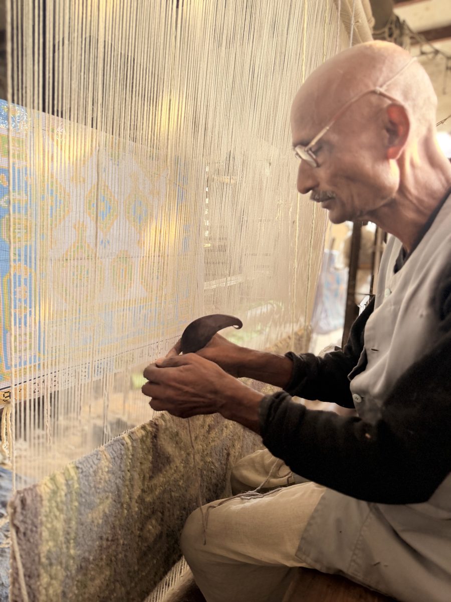 Weaver tying knots at a hand-knotted rug loom in Bhadohi