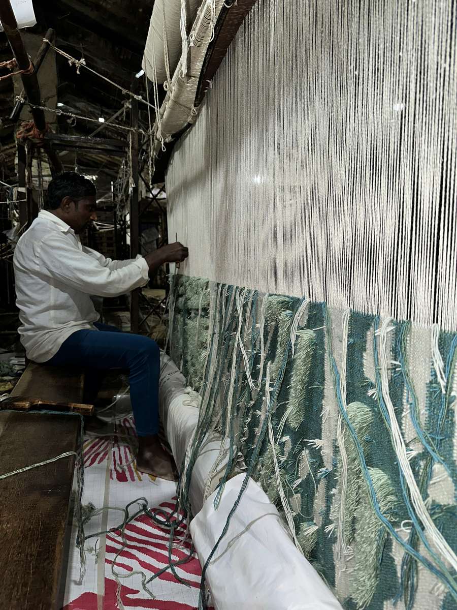 Hand-knotted wool rug in progress on the loom, teal and cream pile