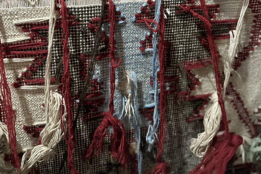 Reverse face of a rug on the loom showing knot structure and yarn ends